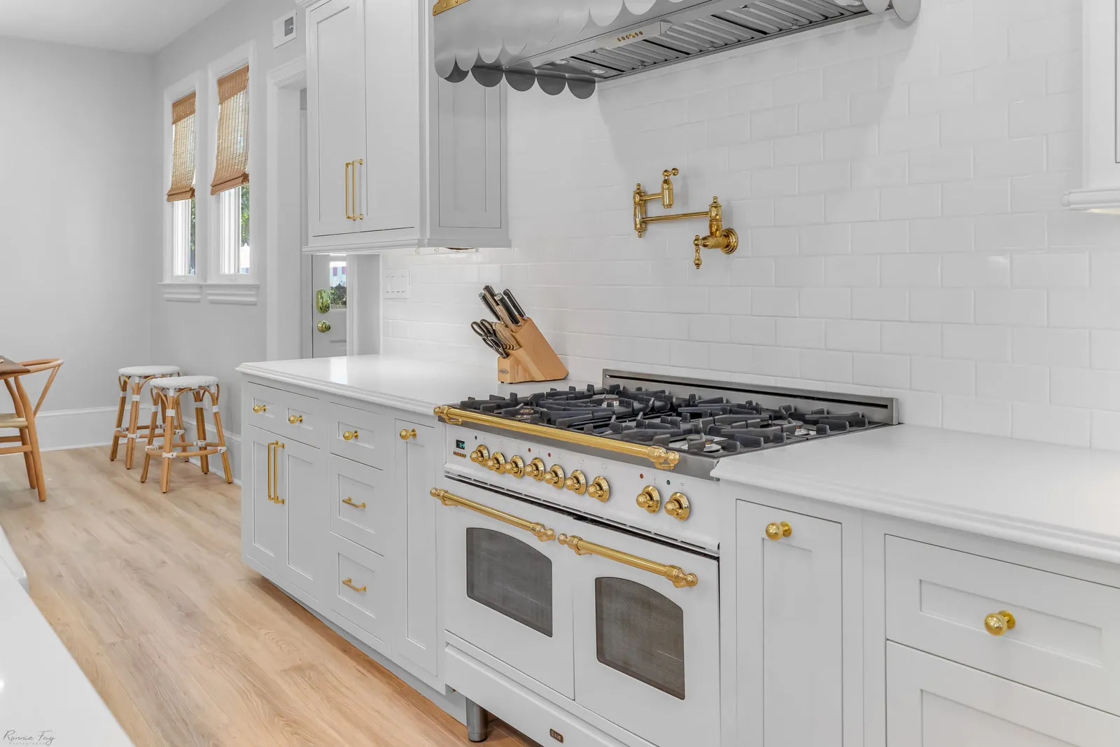 White inset shaker kitchen with professional range, open shelving, and brass hardware